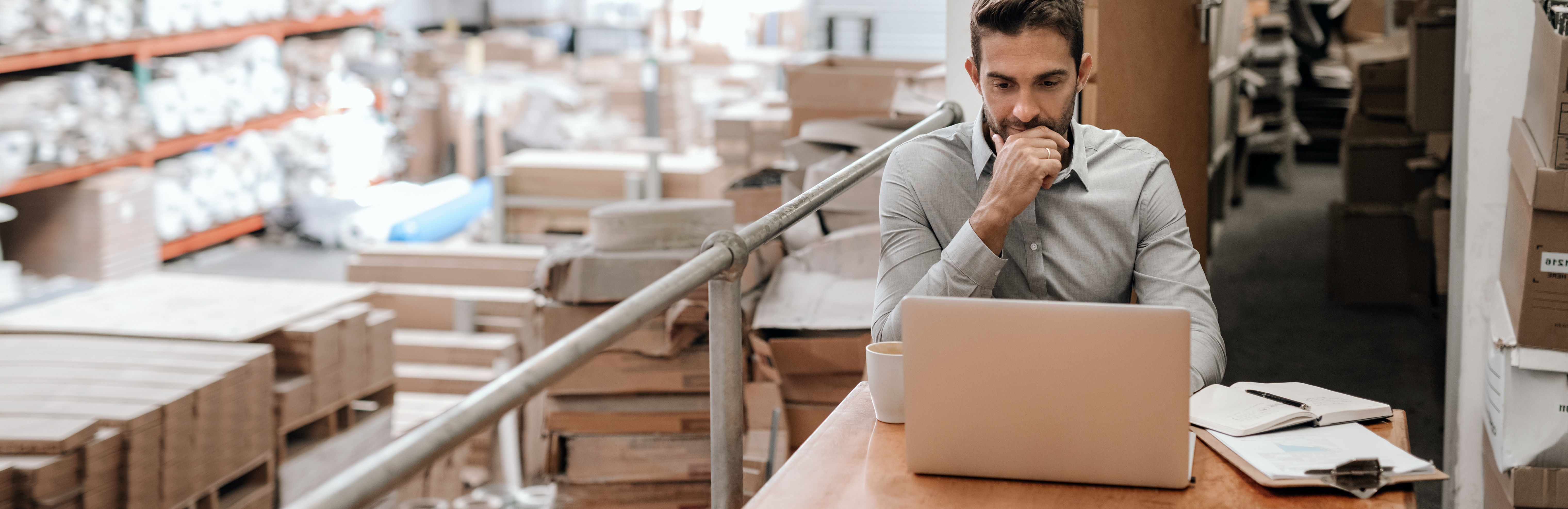 Business owner working on laptop in warehouse of products